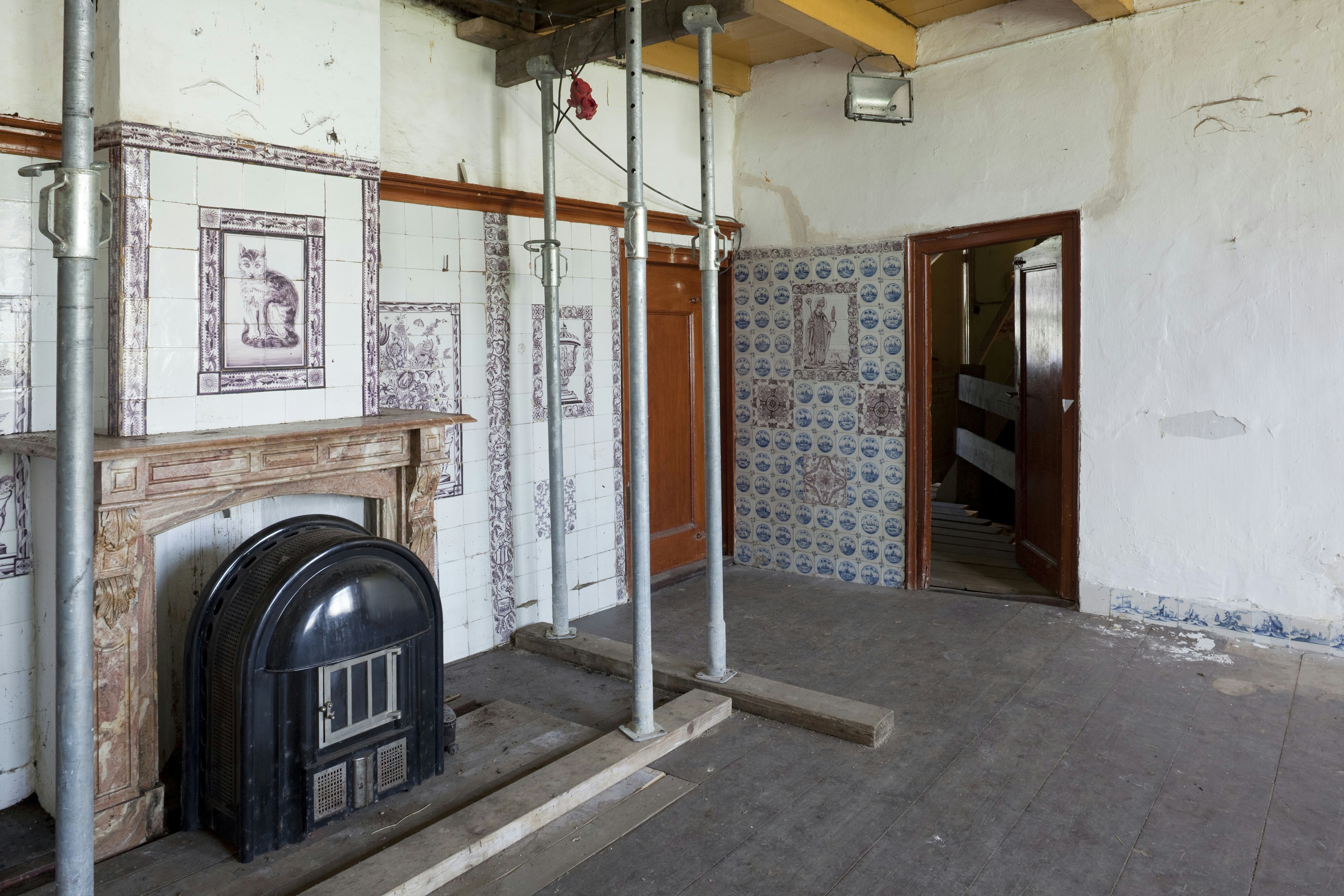 A coal stove beneath the fireplace hood in the tiled room at Gagelgat farmhouse in Soest. A 2009 photograph of a historic interior.