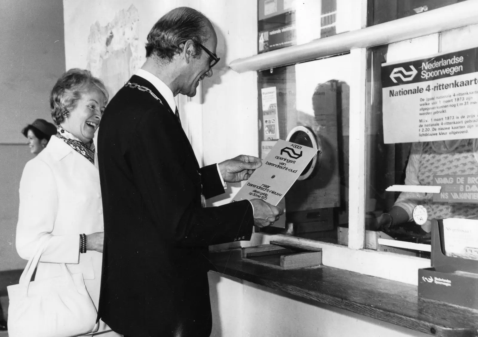 Een reiziger ontvangt in 1973 een treinkaartje aan een loket van NS